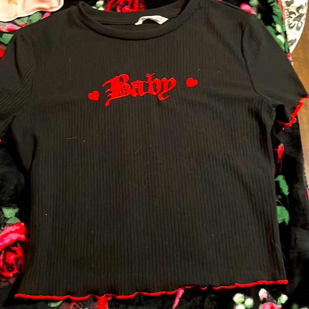 It is a black top with red around sleeves and of the bottom with the word baby.